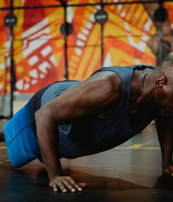 Man performing a strength exercise in a modern, dark gym.