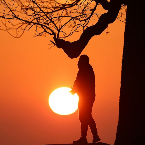 Silhouette of a man stretching against a sunrise.